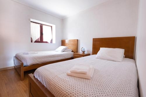 a bedroom with two beds with white sheets and a window at Casa do Meia Noite in Gralhas