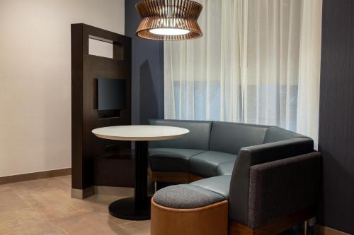 a living room with a couch and a table and a chair at Courtyard by Marriott North Charleston Airport Coliseum in Charleston