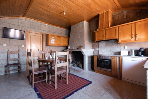 a kitchen with a table and chairs and a fireplace at Casa do Meia Noite in Gralhas