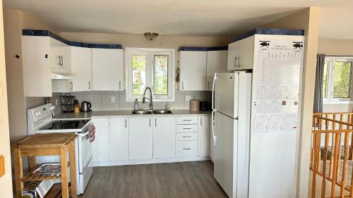 una cucina con mobili bianchi e un frigorifero bianco di Chalet Bleu a Lac Sainte-Marie