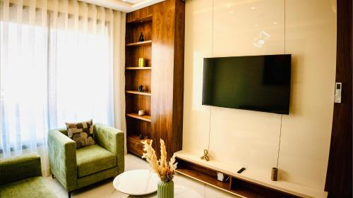 a living room with a tv and a chair and a table at Green Haven- Nature & Design - Riad Extension in Temara