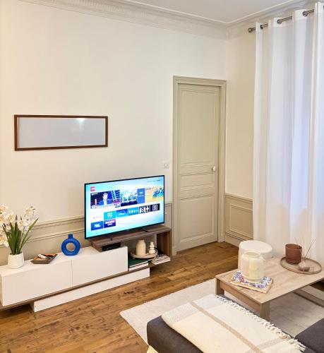 un salon avec une télévision à écran plat sur un mur blanc dans l'établissement Appartement Privé Chic Paris - Tour Eiffel, à Paris
