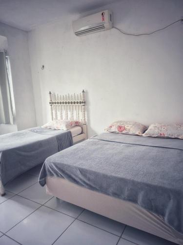 a bedroom with two beds and a air conditioner on the wall at Praia do Paraíso in Mosqueiro