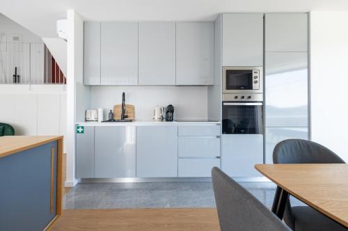 a white kitchen with white cabinets and appliances at Casa de Penedones - Ventos de Barroso in Penedones