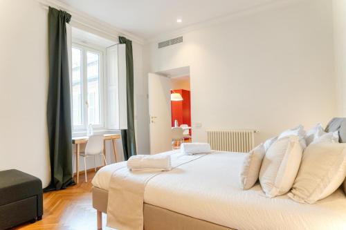 una camera bianca con un grande letto con cuscini bianchi di Cadorna Prestigious Apartment - Modern Architecture in front of the Station a Milano