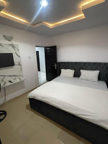 Un dormitorio con una gran cama blanca y un televisor. en Gold House 40, en Ibadán