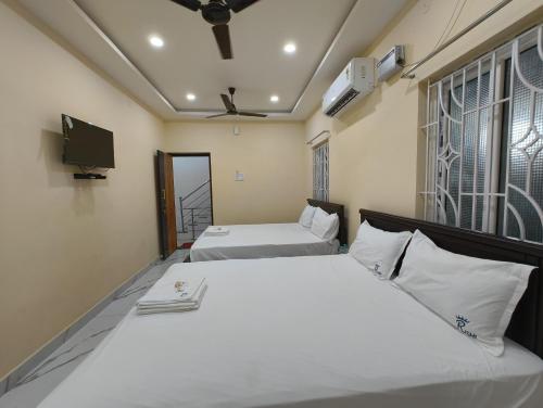 a bedroom with two beds and a tv on the wall at Rishi Residency in Rāmeswaram
