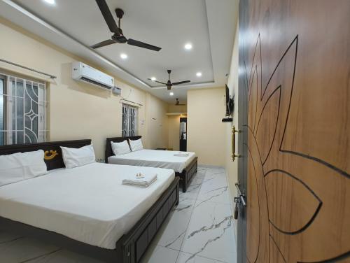 a bedroom with two beds and a door to a room at Rishi Residency in Rāmeswaram