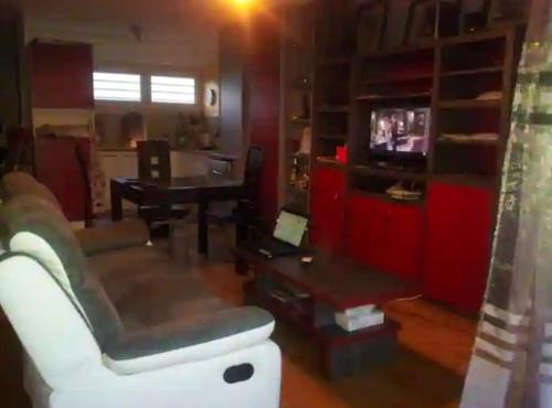 a living room with a couch and a television at 1 chambre dans ma maison in Mérignac