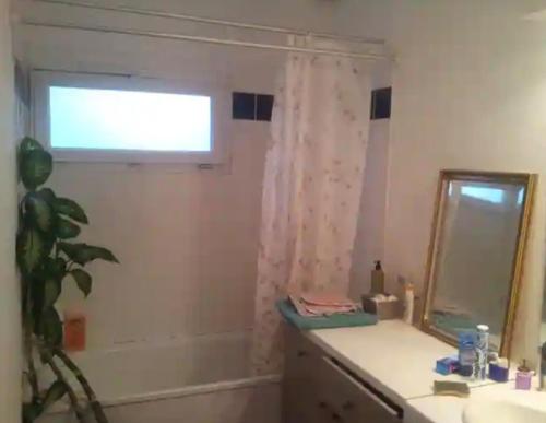 a bathroom with a sink and a mirror and a window at 1 chambre dans ma maison in Mérignac