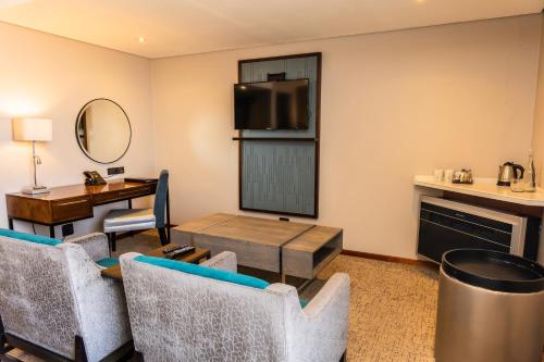a living room with a table and chairs and a television at Premier Splendid Inn Bloemfontein in Bloemfontein