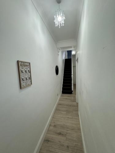 a hallway with white walls and a chandelier at Absam Homes in London