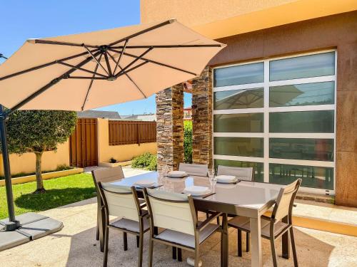 a table and chairs with an umbrella on a patio at Casa Atlântico - 5 minutes from the beach in Viana do Castelo