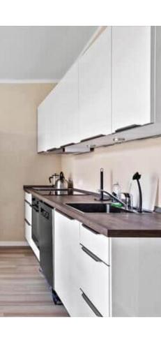 a white kitchen with a sink and a stove at Bøtøstrand ferielejlighed 6 in Marielyst