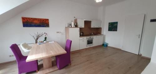 a kitchen with a wooden table and purple chairs at Haus zur Maut in Graz