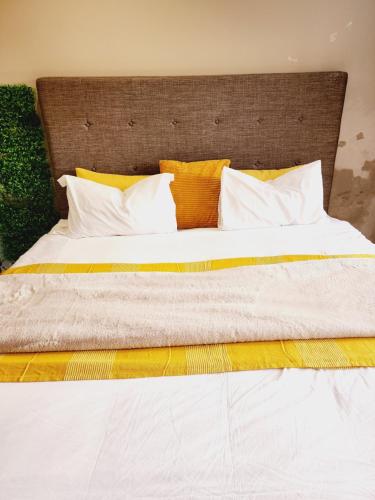 a large bed with yellow and white pillows on it at Eastern Road Executive Suites in Harare