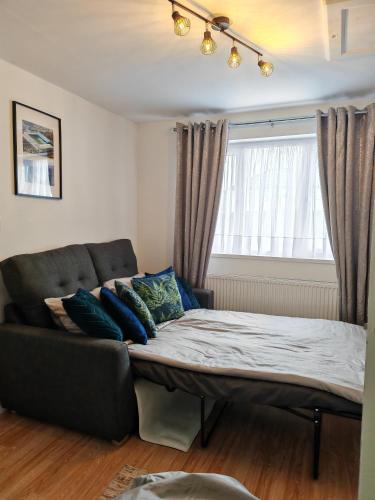 a bed in a living room with a couch and a window at Chota Gher Apartment in Widnes
