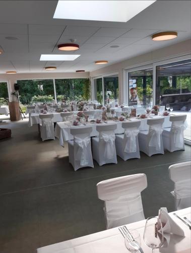 a banquet hall with white tables and white chairs at Hotel Grünwalde in Halle Westfalen