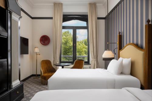 a hotel room with two beds and a window at Hotel Des Indes The Hague in The Hague