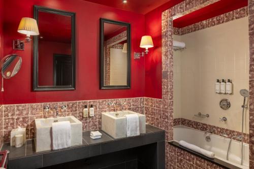 a bathroom with red walls and two sinks and a tub at Hotel Des Indes The Hague in The Hague