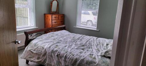 an unmade bed in a bedroom with two windows at The Swallow in Ballybogy