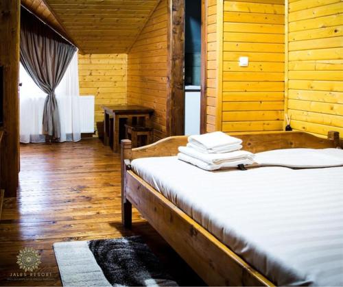 a wooden room with a bed with towels on it at Jales Resort in Sânâteşti