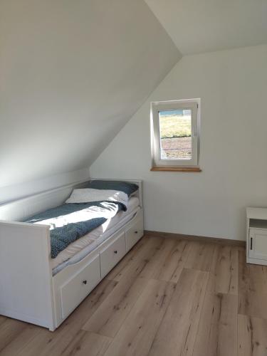 a white bedroom with a bed in the attic at Ptasi Śpiew in Grzędy