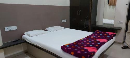 a bed in a room with a flower patterned blanket on it at Vijayalakshmi Lodge in Pandharpur