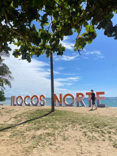 a person walking in front of a sign on the beach at M11 Z Guest House in Pasuquin