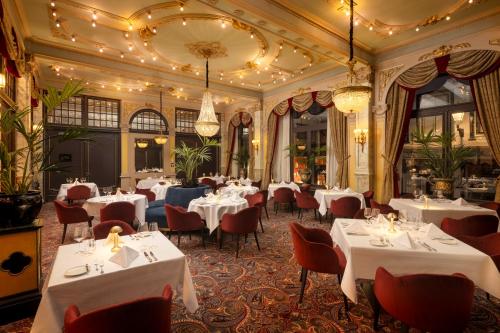 a restaurant with white tables and red chairs at Hotel Des Indes The Hague in The Hague