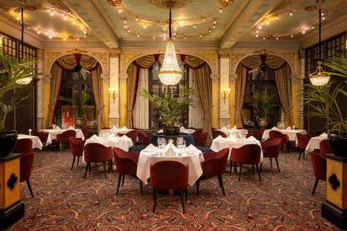 a dining room with tables and chairs and a chandelier at Hotel Des Indes The Hague in The Hague