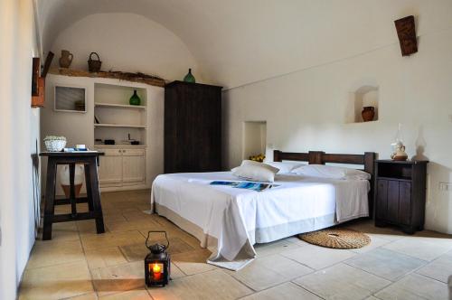 a bedroom with a white bed and a kitchen at Masseria Uccio in Tricase