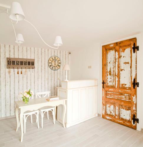 a white room with a table and chairs and a clock at Barackvirág Apartmanház in Tihany