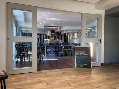 a dining room with a table with chairs and a sign at Brit Hotel Baillet-en-France in Baillet-en-France