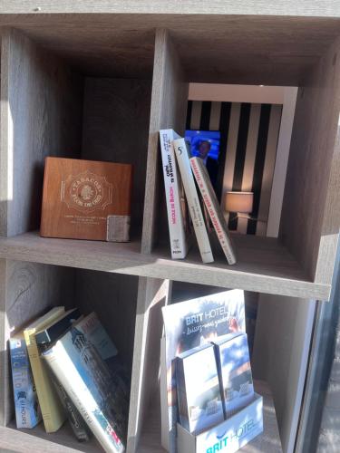 a book shelf with books and a box on it at Brit Hotel Baillet-en-France in Baillet-en-France