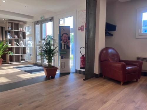 a lobby with a chair and a picture of a man at Brit Hotel Baillet-en-France in Baillet-en-France