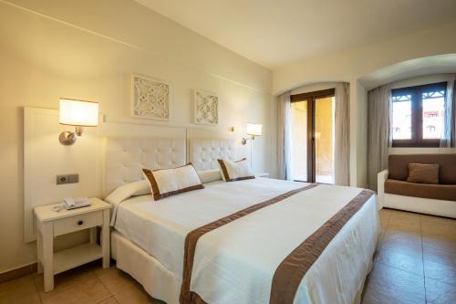 a bedroom with a large white bed and a couch at Vila Gale Isla Canela in Isla Canela