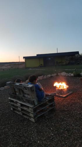 two people sitting on a bench next to a fire at ILLU Resort in Orhei
