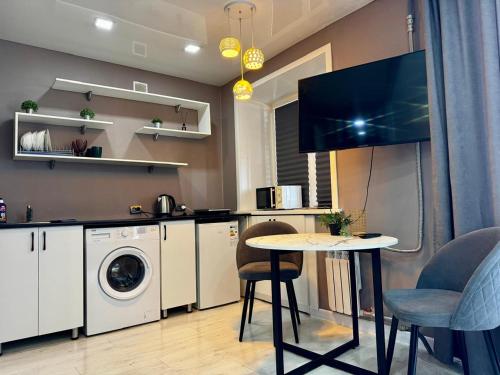 a kitchen with a washing machine and a table at Квартира с видом на Усть-Каменогорск in Ustʼ-Kamenogorsk
