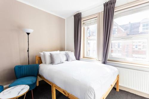 a bedroom with a large white bed and a blue chair at Modern Ealing Studio Apartments, London in Ealing