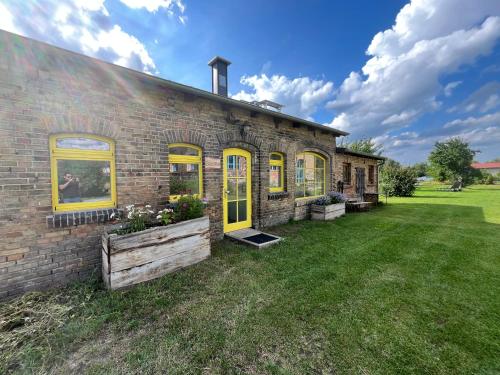 a brick house with yellow doors and a yard at Pension Bäumi-Hof in Seehausen