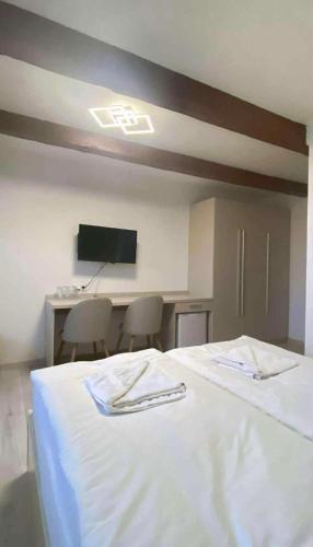 a bedroom with a white bed with two chairs and a screen at Hotel U Radnice Aš in Aš