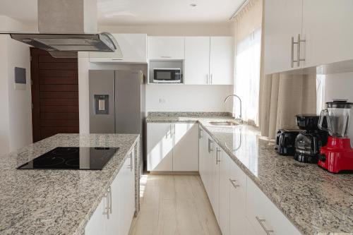 Una cocina con gabinetes blancos y encimeras de granito. en Penthouse Blue Luxury Kukulkan, en Tulum