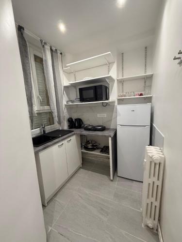 une petite cuisine avec un évier et un micro-ondes dans l'établissement Appartement Tour Eiffel Motte Picquet Fondary, à Paris