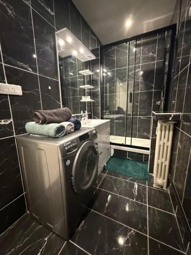 La salle de bains est pourvue de carrelage noir et d'un lave-linge. dans l'établissement Appartement Tour Eiffel Motte Picquet Fondary, à Paris