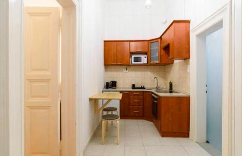 a small kitchen with wooden cabinets and a stool at Stylish Flat in Jewish District 7 in Budapest