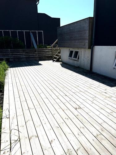a wooden deck in front of a building at Cozy Holiday Home in Sandavágur