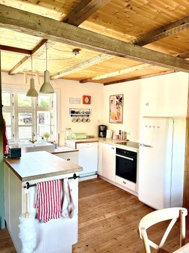 a kitchen with white appliances and a wooden ceiling at Cozy Holiday Home in Sandavágur