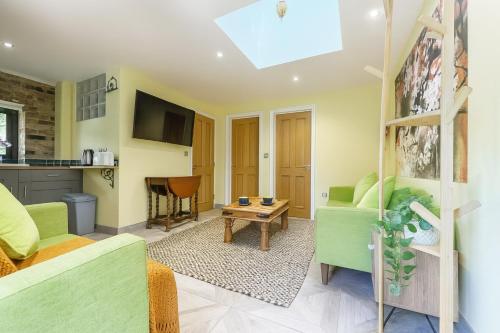 a living room with green furniture and a table at Restful Break 2 BR Woods Cottage 2 Acre Garden gated free Parking in Chislehurst