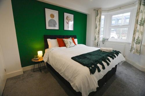 Un dormitorio con una pared verde y una cama en The Tenstay -Contractor-Friendly 5BR Home Close To All, en Ifield